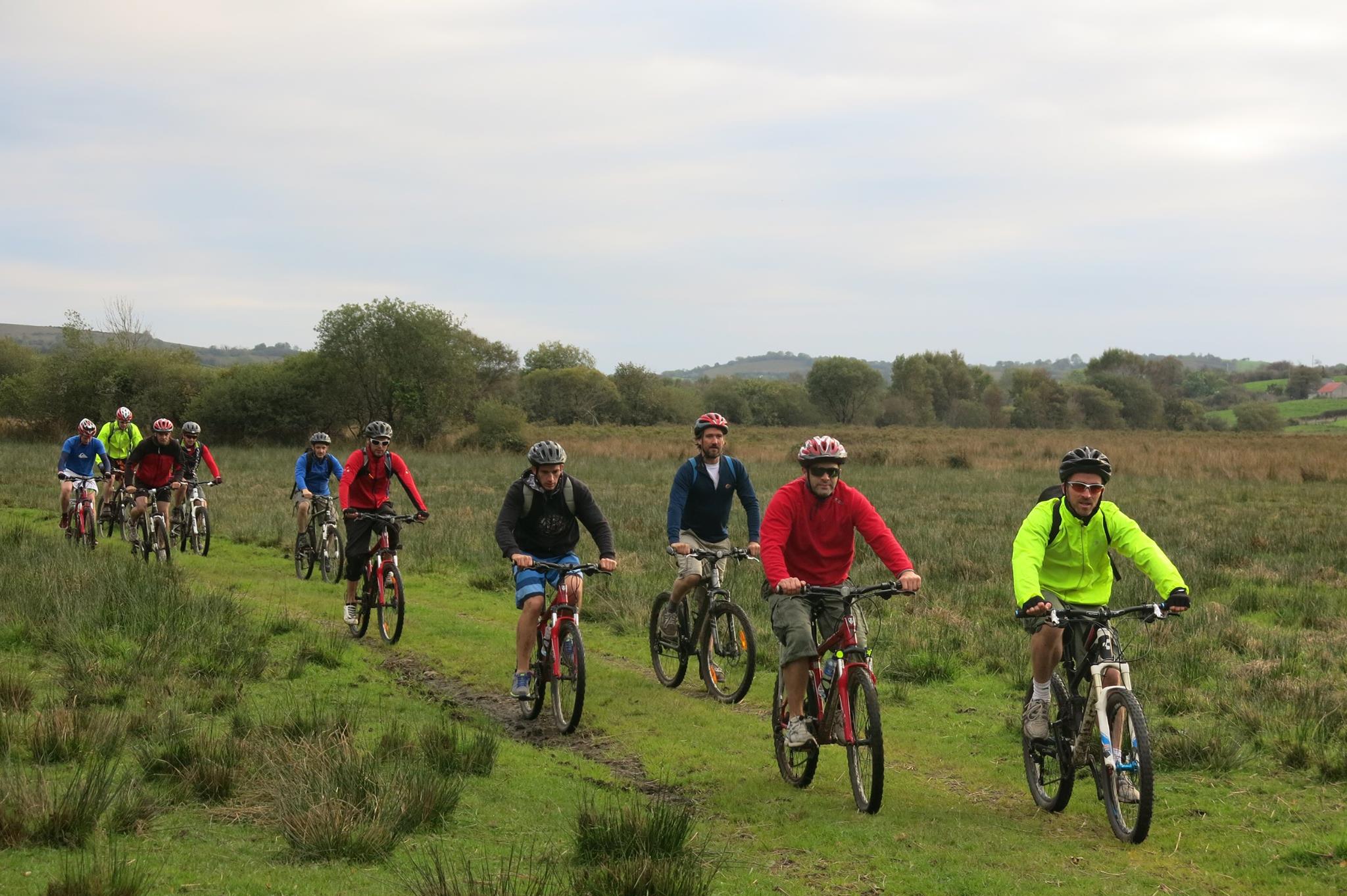 group of people cycling bikes through grass doing biking adventure