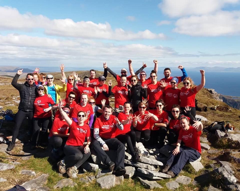 charity group cheering on peak of mountain on hiking adventure